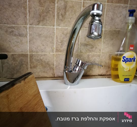 ברז מטבח כסוף מעל כיור לבן
